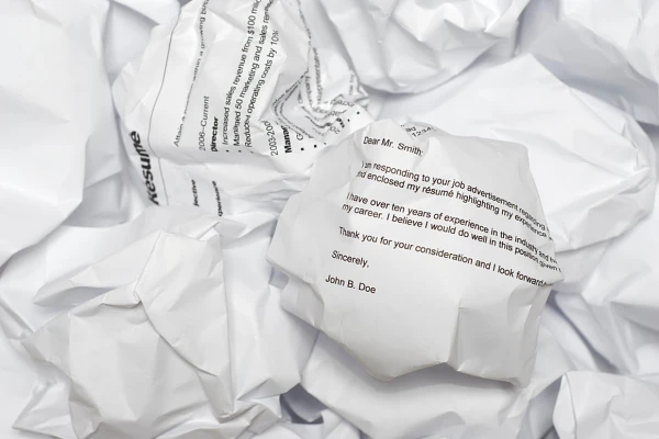 Pile of crumpled papers, a resume and cover letter at the top